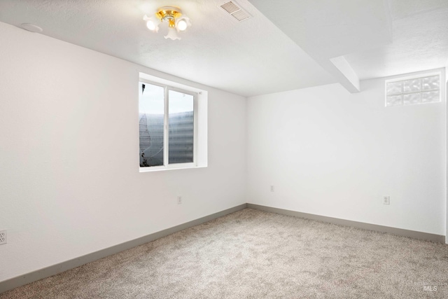 carpeted spare room with visible vents and baseboards