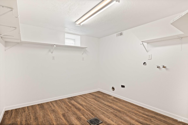 clothes washing area with a textured ceiling, laundry area, wood finished floors, visible vents, and baseboards