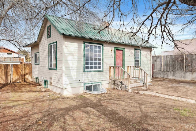 bungalow with metal roof, a chimney, and fence