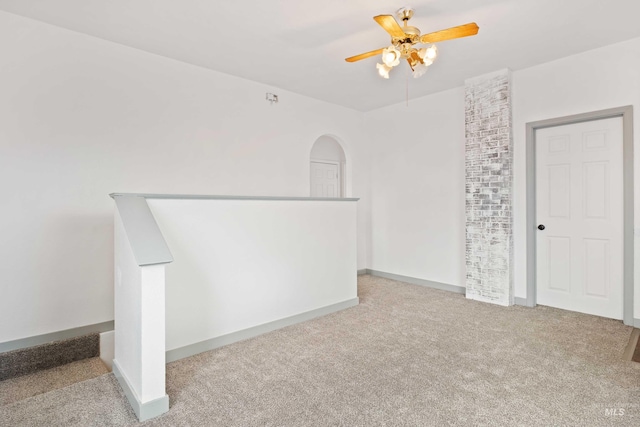 unfurnished room featuring ceiling fan, arched walkways, carpet flooring, and baseboards