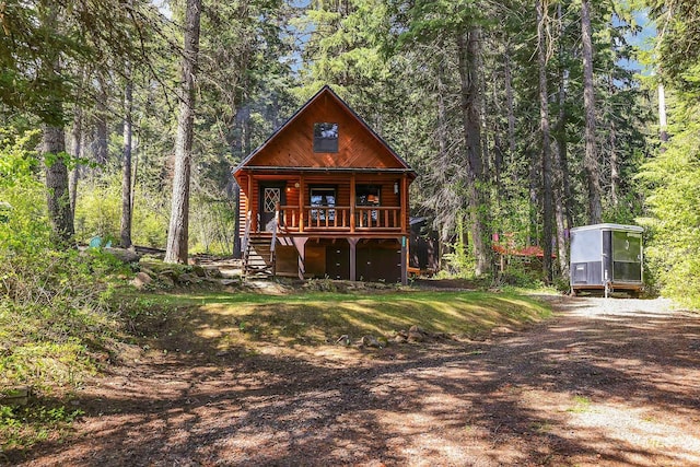 1221 Fox Rd, Cascade, ID 83611 - view of front facade with stairs, a view of trees, a deck, and driveway