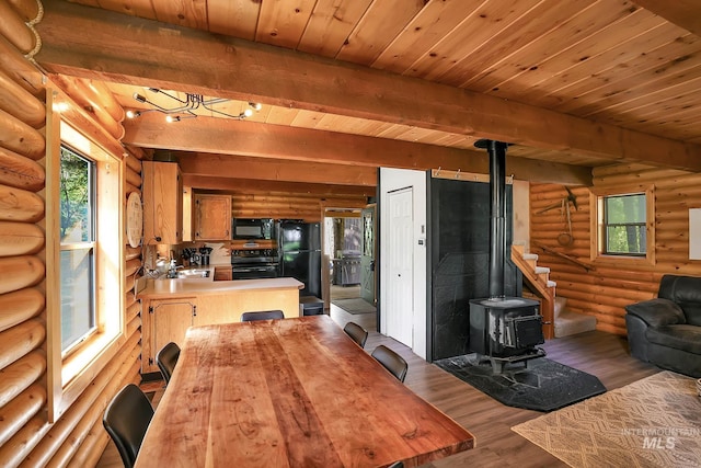 1221 Fox Rd, Cascade, ID 83611 - kitchen featuring black appliances, a wood stove, log walls, open floor plan, and wood finished floors
