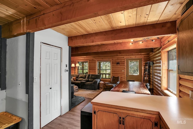 1221 Fox Rd, Cascade, ID 83611 - kitchen with log walls, light wood-style flooring, wooden ceiling with exposed beams, a peninsula, and light countertops
