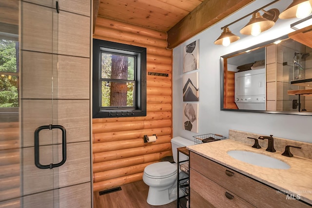 1221 Fox Rd, Cascade, ID 83611 - bathroom with stacked washer / drying machine, log walls, wood finished floors, toilet, and vanity