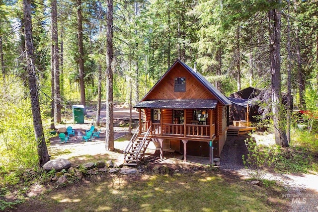 1221 Fox Rd, Cascade, ID 83611 - view of front of home with covered porch, a view of trees, log siding, and stairway