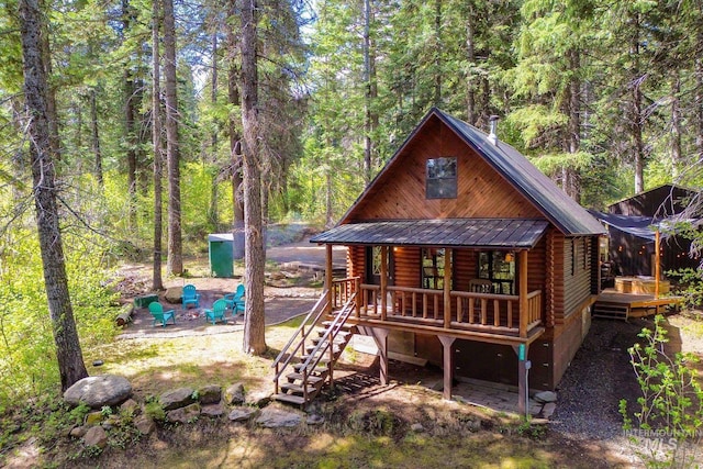 1221 Fox Rd, Cascade, ID 83611 - view of front of property featuring log siding, a forest view, metal roof, and covered porch