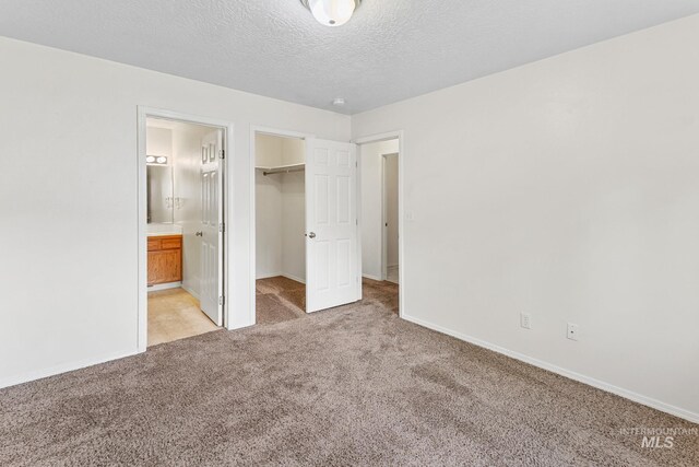3000 E Ohio Ave, Nampa, ID 83686 - unfurnished bedroom featuring light carpet, a walk in closet, baseboards, a closet, and a textured ceiling