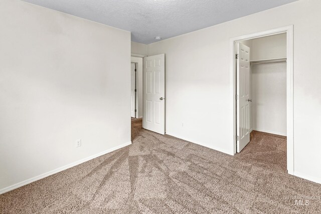 3000 E Ohio Ave, Nampa, ID 83686 - unfurnished bedroom with carpet, a walk in closet, baseboards, a textured ceiling, and a closet