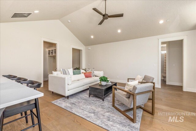 living room with light hardwood / wood-style floors, ceiling fan, and lofted ceiling