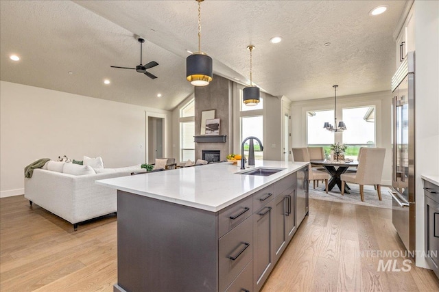 kitchen with a textured ceiling, pendant lighting, sink, and an island with sink