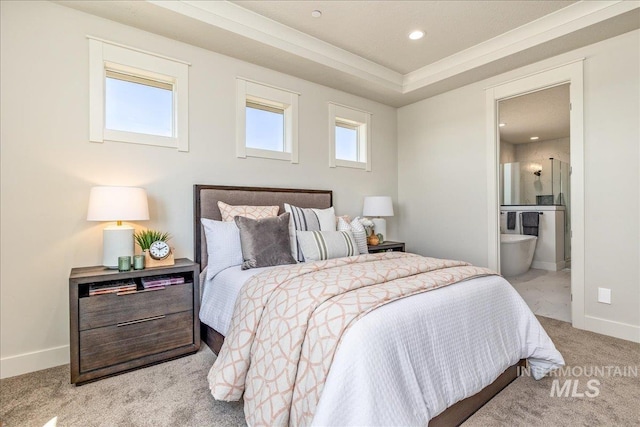 carpeted bedroom featuring a tray ceiling, connected bathroom, and multiple windows