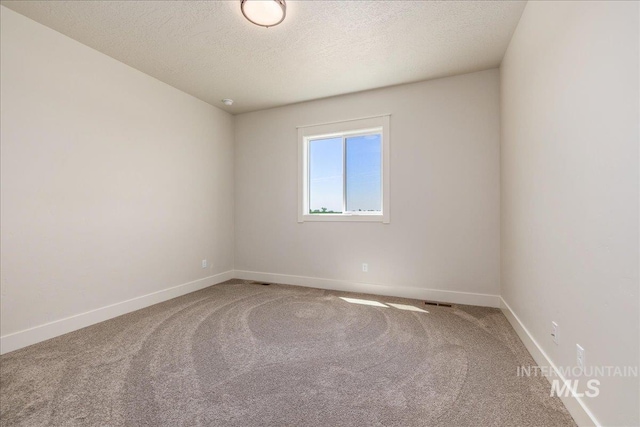 empty room with carpet floors and a textured ceiling