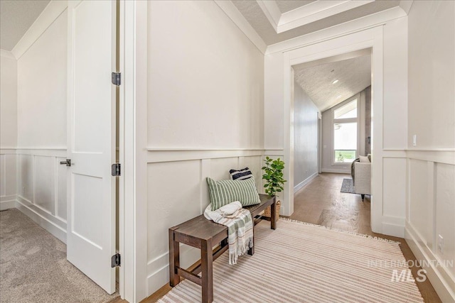 hall with a textured ceiling, lofted ceiling, and ornamental molding