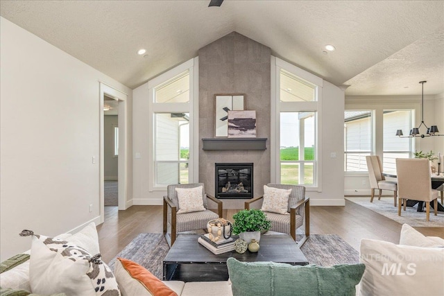 living room with a textured ceiling, a large fireplace, hardwood / wood-style floors, and lofted ceiling