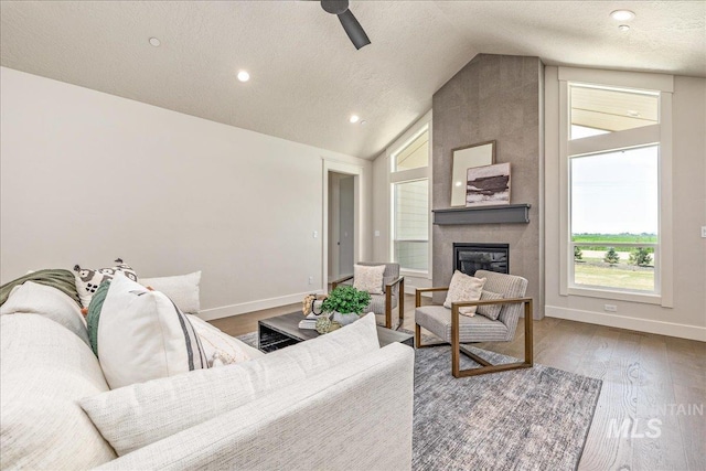 living room featuring hardwood / wood-style flooring, plenty of natural light, a fireplace, and vaulted ceiling