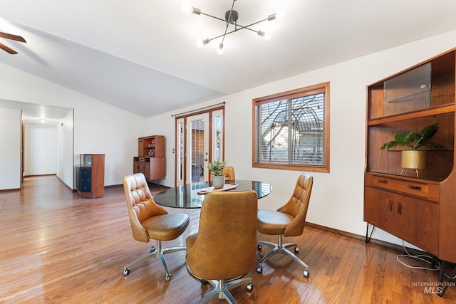 dining room with an inviting chandelier, vaulted ceiling, light wood-style flooring, and baseboards