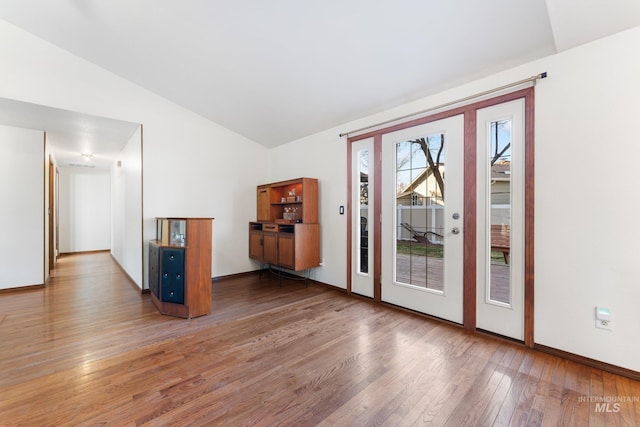 spare room with baseboards, lofted ceiling, and wood-type flooring