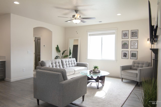 living area featuring arched walkways, visible vents, dark wood finished floors, and baseboards