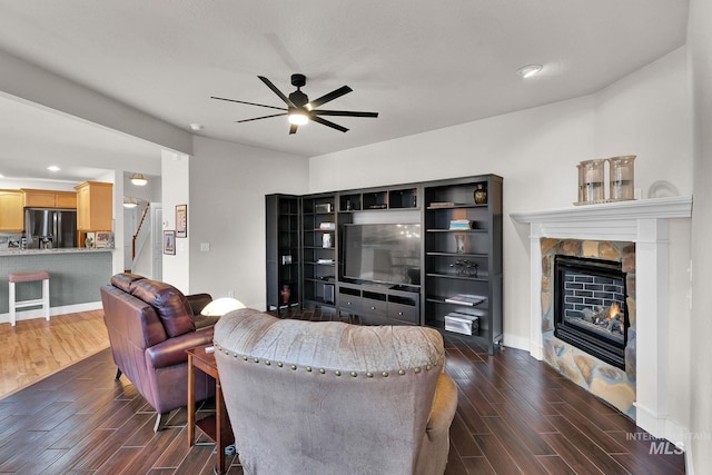 living room featuring baseboards, dark wood finished floors, ceiling fan, stairs, and a fireplace