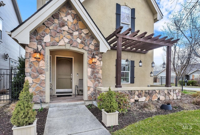 doorway to property featuring stone siding, a pergola, fence, and stucco siding