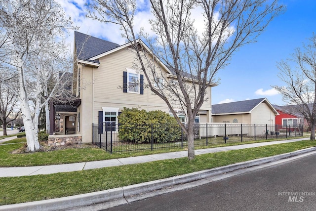 view of front of house with a fenced front yard, a front yard, and a shingled roof