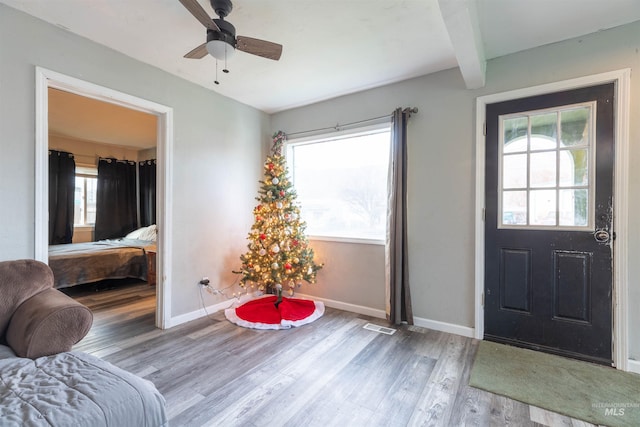 entryway with hardwood / wood-style flooring, ceiling fan, and beamed ceiling