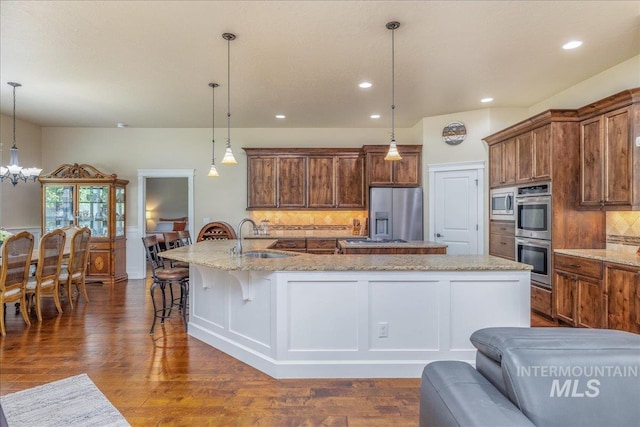 11954 W Meadowfalls Dr, Star, ID 83669 - kitchen with stainless steel appliances, a large island with sink, decorative backsplash, dark wood-style flooring, and a chandelier