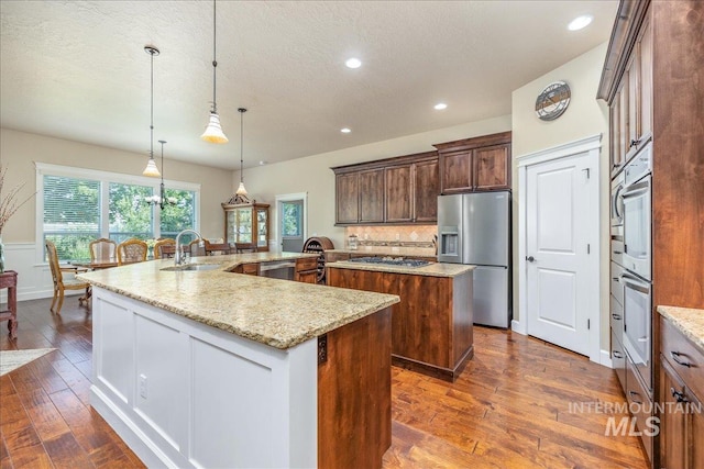 11954 W Meadowfalls Dr, Star, ID 83669 - kitchen featuring stainless steel appliances, a spacious island, dark wood-style flooring, a textured ceiling, and recessed lighting