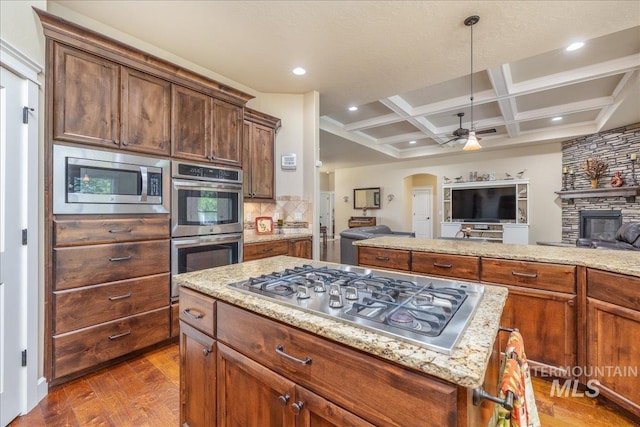 11954 W Meadowfalls Dr, Star, ID 83669 - kitchen featuring stainless steel appliances, open floor plan, arched walkways, ceiling fan, and light stone counters