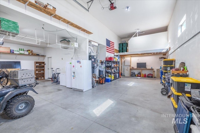 11954 W Meadowfalls Dr, Star, ID 83669 - garage featuring a garage door opener, white refrigerator with ice dispenser, freestanding refrigerator, and a workshop area