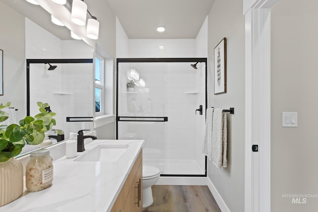 bathroom featuring hardwood / wood-style floors, vanity, toilet, and a shower with door