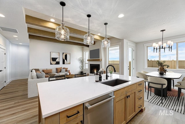 6998 S Tindaris Ave, Meridian, ID 83642 - kitchen featuring stainless steel dishwasher, light wood finished floors, a lit fireplace, decorative light fixtures, and recessed lighting