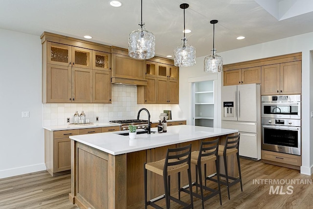 6998 S Tindaris Ave, Meridian, ID 83642 - kitchen with white fridge with ice dispenser, stainless steel double oven, light wood finished floors, backsplash, and a kitchen island with sink