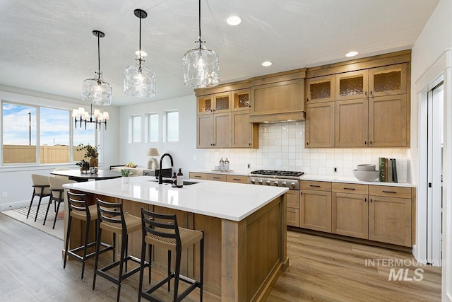 6998 S Tindaris Ave, Meridian, ID 83642 - kitchen featuring a kitchen island with sink, light wood-type flooring, light countertops, backsplash, and recessed lighting