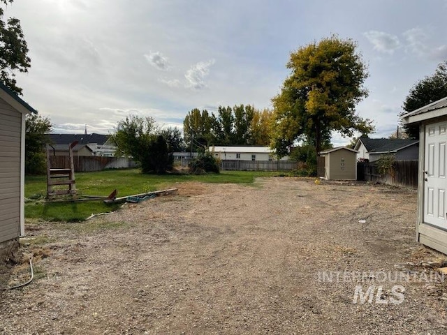 view of yard featuring a storage shed, a fenced backyard, and an outbuilding