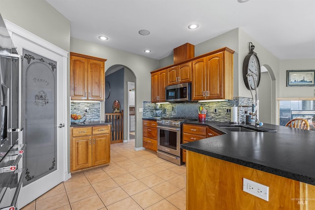 2570 Reservoir Rd, Clarkston, WA 99403 - kitchen with stainless steel appliances, arched walkways, dark countertops, decorative backsplash, and light tile patterned flooring