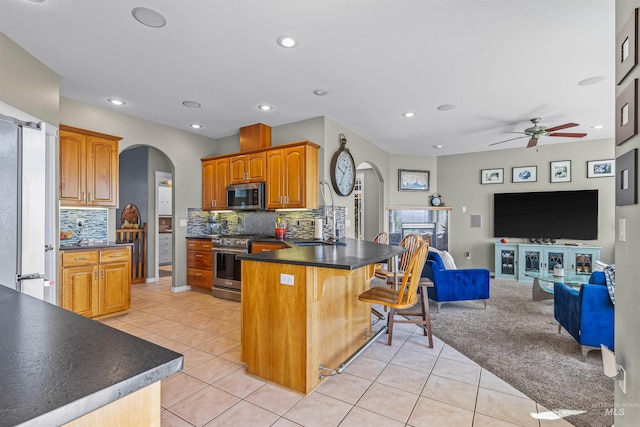 2570 Reservoir Rd, Clarkston, WA 99403 - kitchen featuring appliances with stainless steel finishes, arched walkways, a peninsula, open floor plan, and light tile patterned floors