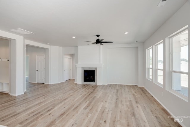 unfurnished living room with light hardwood / wood-style flooring, a large fireplace, and ceiling fan