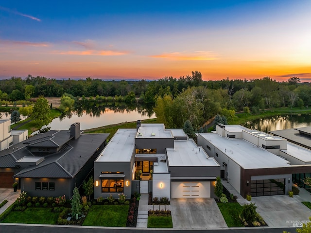 aerial view at dusk featuring a water view