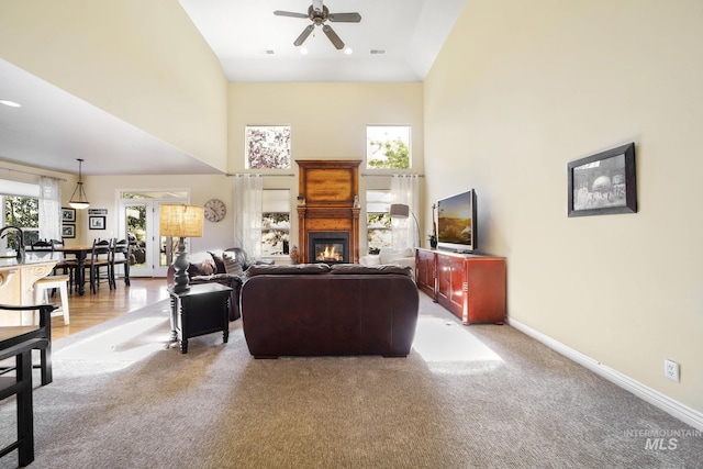 3408 Ridgeline Dr, Kimberly, ID 83341 - living room featuring baseboards, a towering ceiling, a ceiling fan, a glass covered fireplace, and light colored carpet