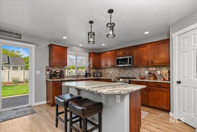 4226 E Tahiti St, Meridian, ID 83646 - kitchen with stainless steel appliances, light wood-style flooring, tasteful backsplash, a kitchen island, and a breakfast bar area