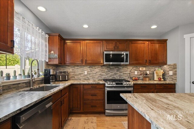 4226 E Tahiti St, Meridian, ID 83646 - kitchen featuring stainless steel appliances, light wood finished floors, light stone countertops, tasteful backsplash, and recessed lighting