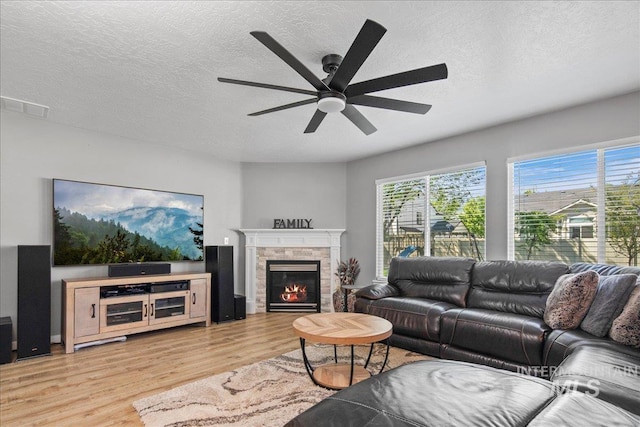 4226 E Tahiti St, Meridian, ID 83646 - living area with plenty of natural light, a ceiling fan, light wood-style floors, a textured ceiling, and a glass covered fireplace