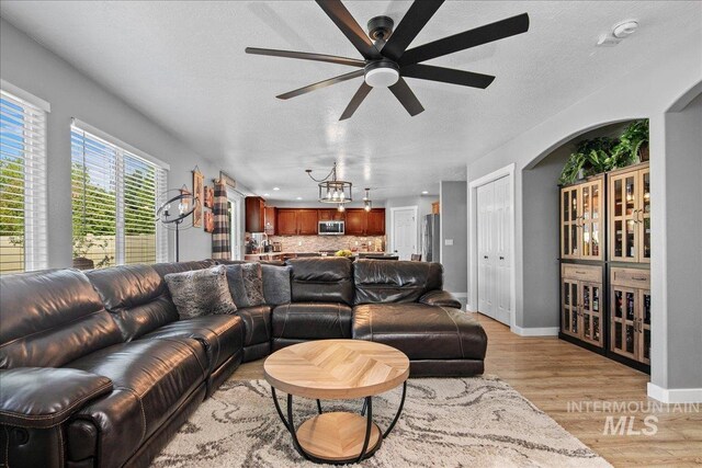 4226 E Tahiti St, Meridian, ID 83646 - living room featuring arched walkways, light wood finished floors, ceiling fan, a textured ceiling, and baseboards