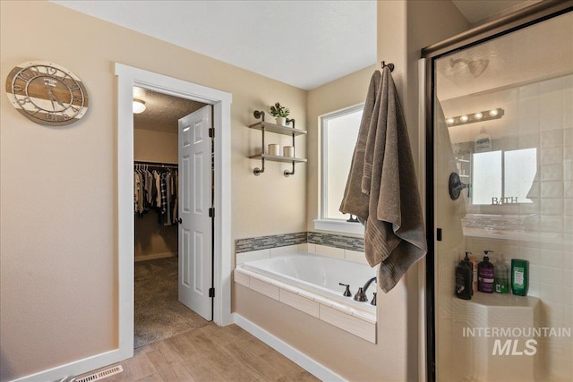 4226 E Tahiti St, Meridian, ID 83646 - full bathroom featuring a stall shower, wood finished floors, a bath, a spacious closet, and baseboards