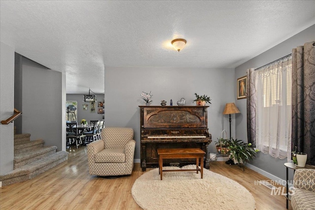 4226 E Tahiti St, Meridian, ID 83646 - sitting room featuring light wood-style flooring, stairs, baseboards, and a textured ceiling