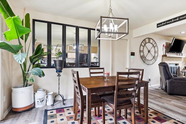 dining room with a chandelier, wood-type flooring, and a fireplace