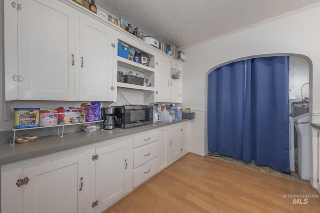538 N 6th St, Payette, ID 83661 - kitchen featuring stainless steel microwave, light wood-style floors, a textured ceiling, arched walkways, and crown molding