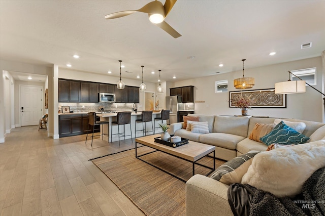 living room with light hardwood / wood-style flooring and ceiling fan