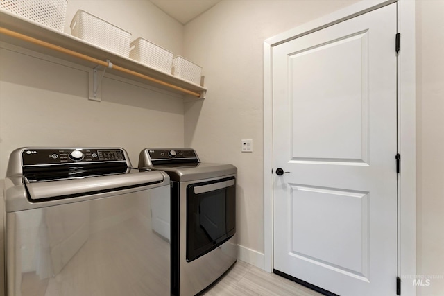 laundry room with washing machine and dryer and light hardwood / wood-style floors